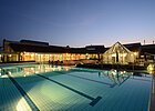 Die Therme und das Außenbecken hell erleuchtet in der Nacht.