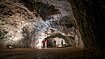 Mehrere Besucher bestaunen die große Tropfsteinhöhle, diese gut beleuchtet.